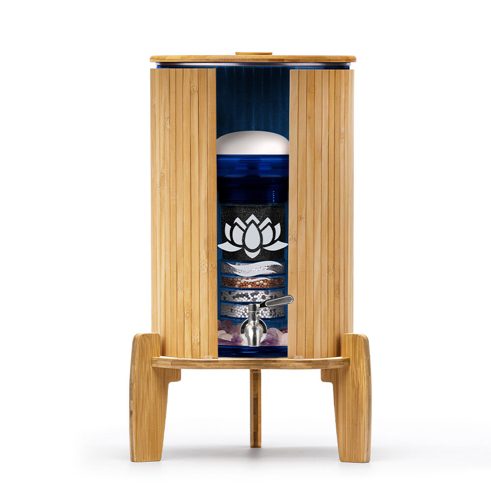 Ein Stand-Wasserfilter aus Bambus mit einem blauen Glasbehälter, der im Querschnitt die einzelnen Schichten der Wasserfilterung zeigt.