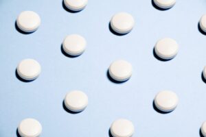 Weiße Tabletten auf blauem Hintergrund als Symbol für Hausmittel gegen Kalk.