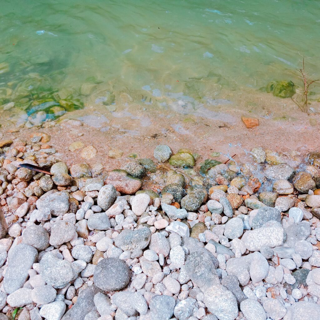 Von der Natur inspiriert: Klares, reines Wasser umspült sanft einen Strand aus runden, glatten Steinen.