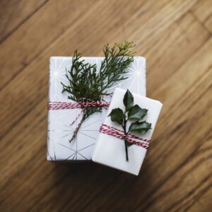 Zwei liebevoll verpackte Weihnachtsgeschenke, mit Naturzweigen dekoriert, symbolisieren nachhaltige und herzliche Geschenkideen.